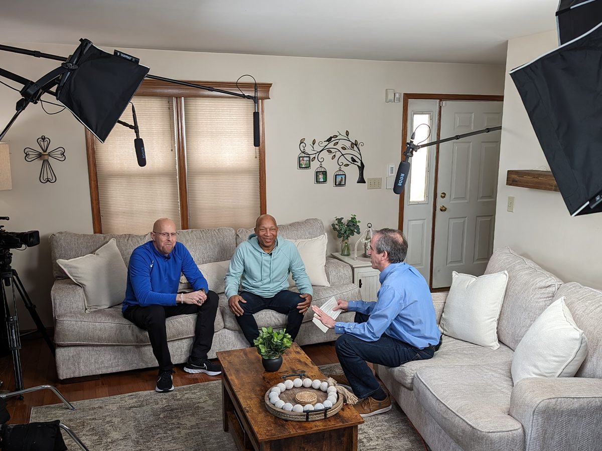 Two guests and a host mid-interview in a living room, lit with softboxes and boomed.