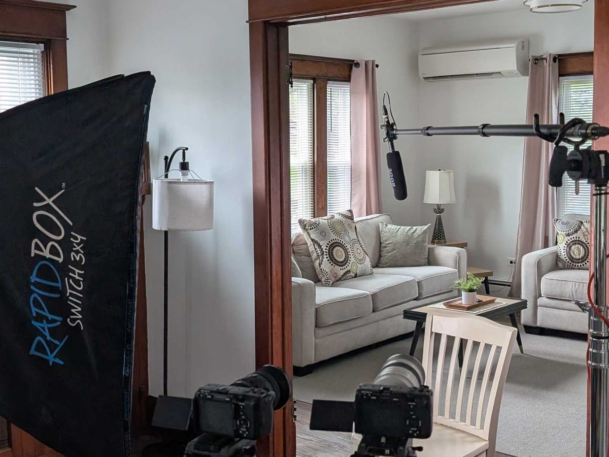 Two cameras and a softbox set up for an interview in a private living room.