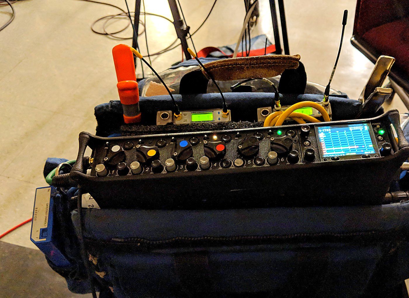 A sound bag on a cart: mixer-recorder, wireless receivers, and headphones resting on top.