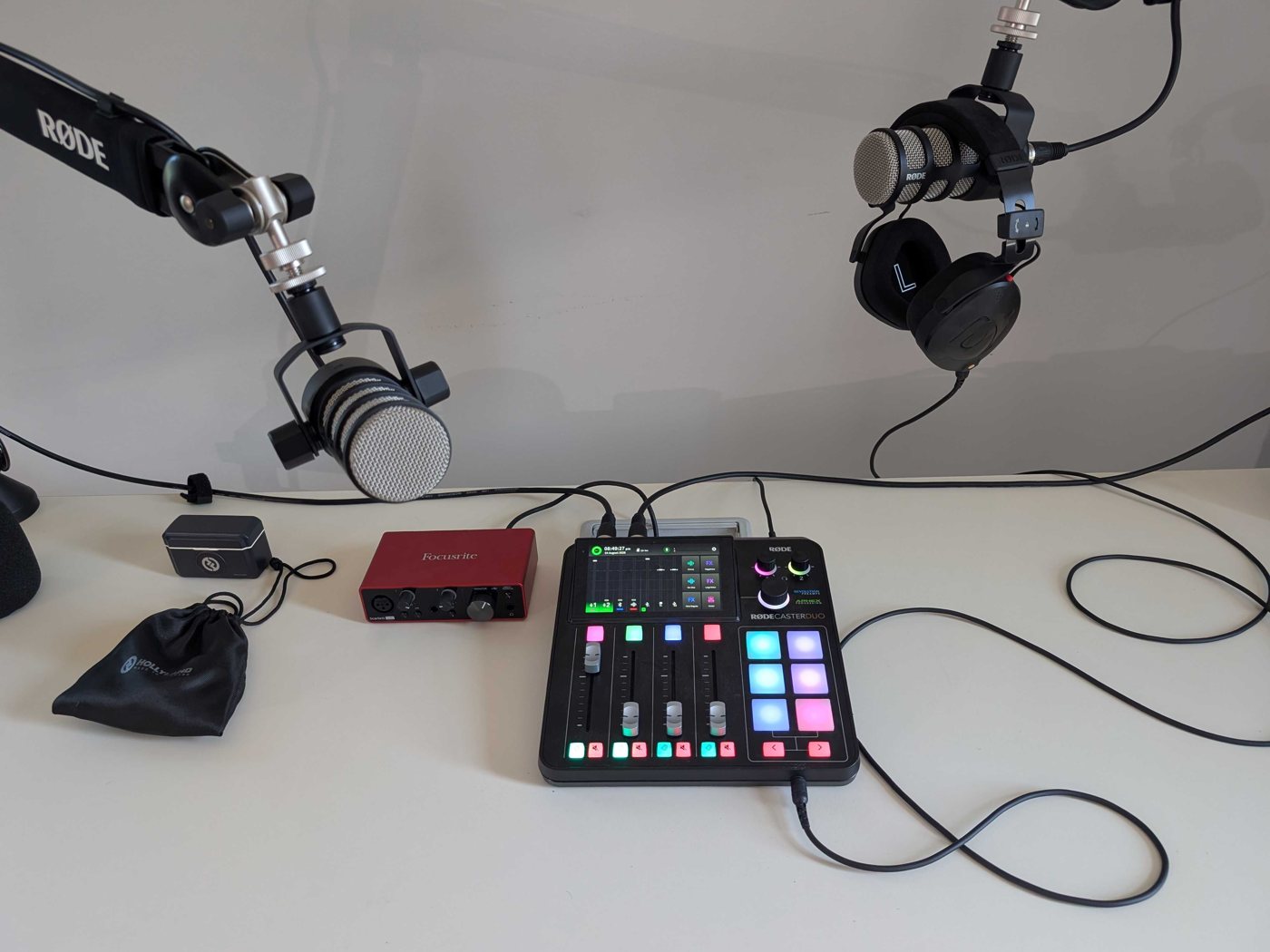 A broadcast audio setup — two RØDE mics on booms, headphones, and a RØDECaster Duo mixer.