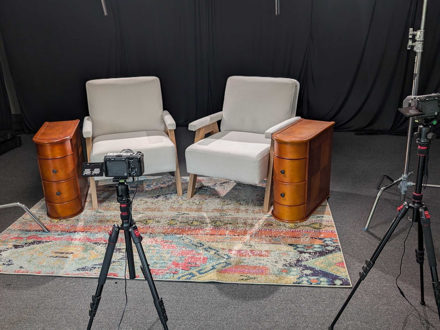 A two-chair video interview set at Studio 1801 — black backdrop, key light, boom mics, and a camera on a tripod.